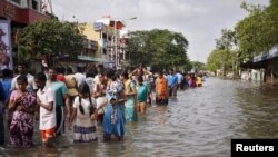 Residents wade through a flooded street as they evacuate their homes in Chennai, in the southern state of Tamil Nadu, India, Dec. 3, 2015. 
