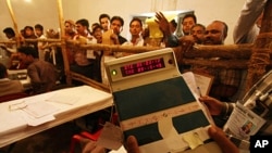 An election official shows an electronic voting machine to poll agents at a counting station in Lucknow, India, March 6, 2012.