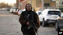 Erick Jordan camina por la calle con su fusil para ofrecer protección, el viernes 19 de noviembre de 2021, en Kenosha, Wisconsin. 