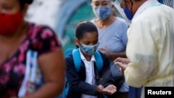 Archivo. Una niña se desinfecta las manos en la puerta de la escuela, el primer día de regreso a la instrucción presencial luego de que fue suspendida por la enfermedad del coronavirus (COVID-19), en Caracas, Venezuela, 25 de octubre de 2021.