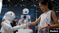 A visitor shakes hands with a humanoid robot at 2018 China International Robot Show in Shanghai, China, July 4, 2018. 