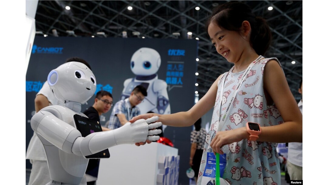 FILE - A visitor shakes hands with a humanoid robot at 2018 China International Robot Show in Shanghai, China, July 4, 2018.
