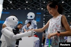 FILE - A visitor shakes hands with a humanoid robot at 2018 China International Robot Show in Shanghai, China, July 4, 2018.