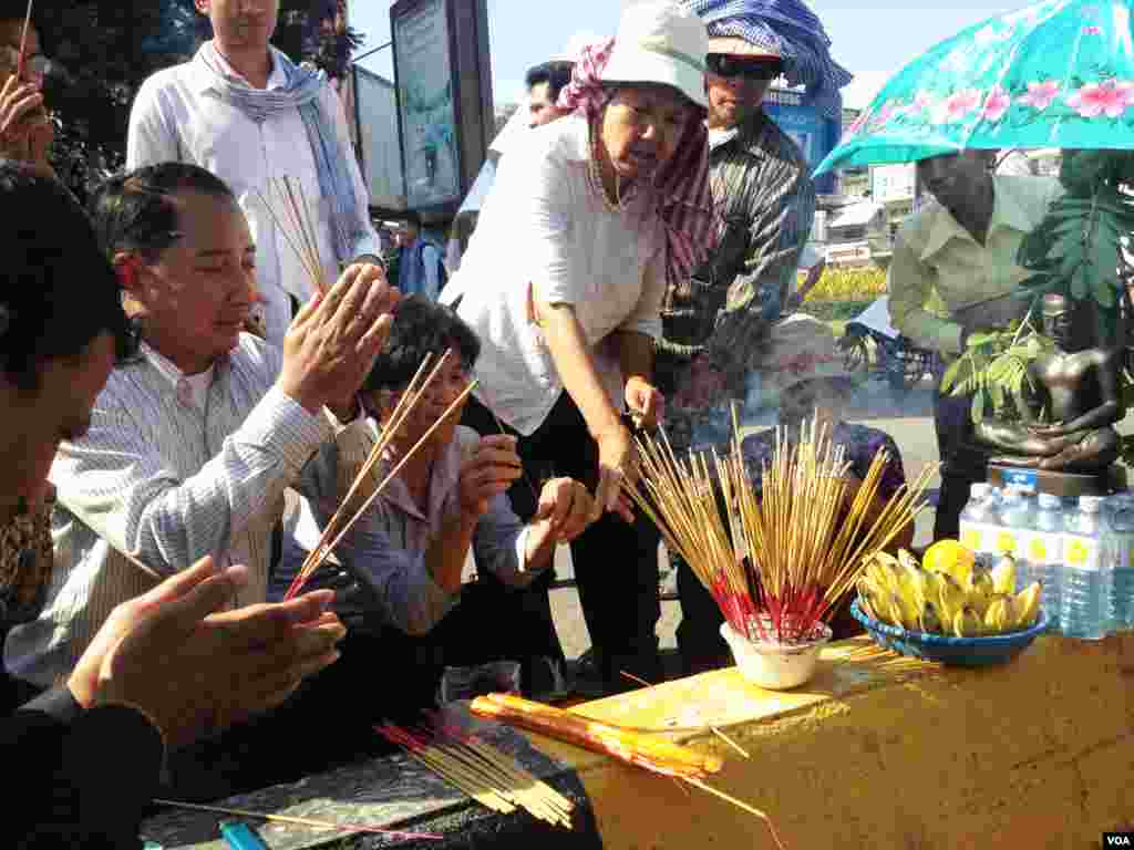 Union leader Ath Thorn (left), of the independent C.CAWDU union, joins supporters to light incense ahead of the verdict in Phnom Penh, Cambodia, May 30, 2014. (Robert Carmichael/VOA)