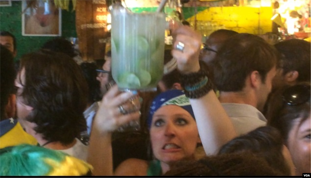 A waitress balances a pitcher as she maneuvers her way through the crowd at Little Favela during the first match of the 2014 World Cup, Brooklyn, New York, June 12, 2014. (Adam Phillips/VOA)