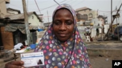 Fatima Bello display her new voters registration card in Lagos, Nigeria, Saturday, Jan. 15, 2011. An effort to register 70 million voters across Nigeria wobbled to life Saturday, as volunteers spread out across Africa's most populous nation ahead of its A