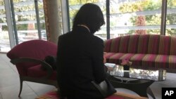 Grace Meng, la esposa del desparecido presidente de Interpol Meng Hongwei, quien no quiere mostrar su rostro, consulta su teléfono móvil en el lobby de un hotel en Lyon, Francia, en donde está basada la agencia policial, el domingo 7 de octubre de 2018. (AP Foto/John Leicester)