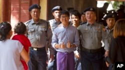 Reuters journalist Wa Lone, center, flashes thumps up as he is escorted by Myanmar police to court for trial, Feb. 1, 2018, on the outskirts of Yangon, Myanmar. The trial resumes for the two Reuters journalists charged of violating state secrets.