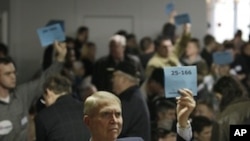 Bill Barnson, left, and others staffing precinct tables at a Washington state Republican caucus meeting, hold up signs showing precinct numbers, Saturday, March, 3, 2012, in Puyallup, Washington. 