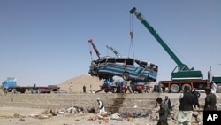 A crane lifts a bus that skidded off the road on Kabul-Kandahar highway in Dama district south of Kabul, Afghanistan, August 20, 2011