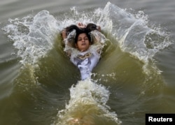 A girl cools off herself in the waters of the river Ganges during a hot summer morning in Allahabad, India, May 31, 2015.