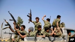 Shi'ite fighters ride on a patrol truck as they chant slogans during a tribal gathering showing support for the Houthi movement in Sana'a, Yemen, Dec. 14, 2015..