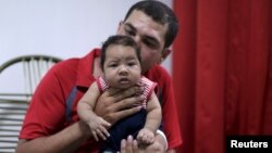 FILE - Glecion Fernando holds his 2-month-old son, Guilherme Soares Amorim, who was born with microcephaly, in Ipojuca, Brazil, Feb. 1, 2016. 