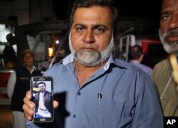 A relative shows a picture of Syed Areeb Ahmed, a Pakistani citizen who was killed the Christchurch mosque shootings, on his cellphone outside his home in Karachi, Pakistan, March 16, 2019. Pakistan's foreign minister says at least six Pakistanis were killed in the shootings.