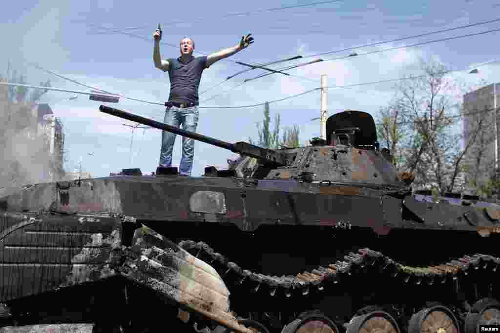 Sharqiy Ukrainaning Mariupol shahridagi buzuq tank ustida mahalliy fuqarolardan biri turibdi, 10-may, 2014-yil.