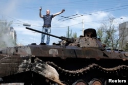 A man reacts as he stands on top of burnt-out armoured personal carrier near the city hall in Mariupol, eastern Ukraine May 10, 2014.