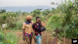 Olivier Lamec and Divine Wisoba walk by the grave of their daughter Maombi on Sept. 3, 2024, in Kamituga, South Kivu province, in eastern Congo.