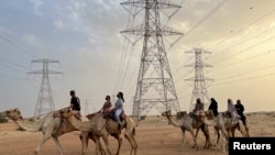 Linda Krockenberger, salah seorang pendiri sekolah, memimpin sekelompok siswa yang mengambil pelajaran menunggang unta di Arabian Desert Camel Riding center di Dubai, Uni Emirat Arab, 1 Agustus 2022. (REUTERS/Abir Al Ahmar)