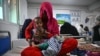 FILE - A woman sits on a hospital bed with her four-month-old twins in the malnutrition ward at the Boost Hospital, run by Medicines Sans Frontiers (MSF), in Lashkar Gah, Helmand, Afghanistan, July 21, 2022.