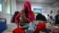 FILE - A woman sits on a hospital bed with her four-month-old twins in the malnutrition ward at the Boost Hospital, run by Medicines Sans Frontiers (MSF), in Lashkar Gah, Helmand, Afghanistan, July 21, 2022.