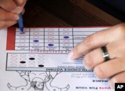 A person completes a ballot in a mock election at Cafecito Bonito in Anchorage, Alaska, where people ranked the performances by drag performers, July 28, 2022.