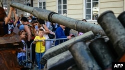 FILE - Bystanders look at Russian military equipment that was destroyed in fights with the Ukrainian army, displayed as part of an outdoor exhibition on central square of Lviv, Ukraine, Aug.11, 2022.