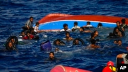 People swim next to their overturned wooden boat during a rescue operation by Spanish NGO Open Arms at south of the Italian Lampedusa island at the Mediterranean sea, Aug. 11, 2022.