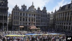 A giant Ukrainian flag is unfurled during an event for Ukrainian Independence Day in the historical Grand Place of Brussels