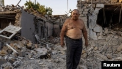 Alexander Shulga with his dog next to him reacts in front of his and his neighbour's home destroyed by a strike, amid Russia's invasion of Ukraine, in Mykolaiv, Ukraine, August 29, 2022.