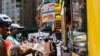 Warga AS yang memakai masker sedang membeli makanan dari pedagang kaki lima di dekat Central Park, di wilayah Manhattan, New York City, AS, 21 Juni 2020. (Foto: REUTERS/Jeenah Moon)