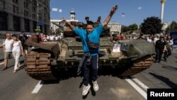 A boy jumps from a tank at an exhibition of destroyed Russian military vehicles and weapons, dedicated to the upcoming country's Independence Day, in the center of Kyiv, Ukraine Aug. 21, 2022.