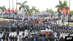 Le cortège transportant la dépouille de l'ancien président angolais José Eduardo dos Santos jusqu'à sa dernière demeure marche derrière le corbillard lors de ses funérailles d'État à la Praca da Republica à Luanda le 28 août 2022. 