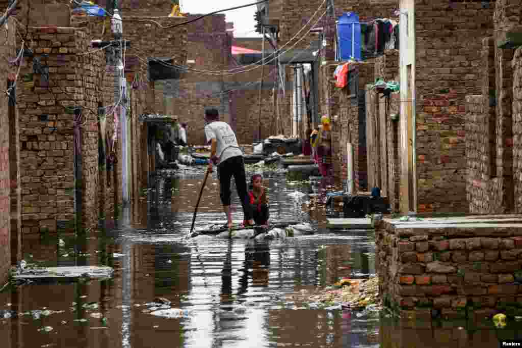 A man and a girl use a makeshift raft as they cross a flooded street, following rains during the monsoon season in Hyderabad, Pakistan, Aug. 24, 2022.