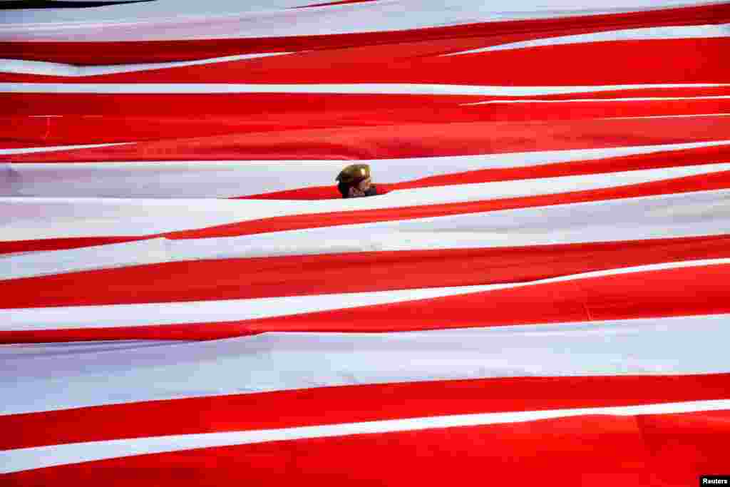 A municipal officer stands among the national flag while celebrating Indonesia's 77th Independence Day at Losari Beach, Makassar, South Sulawesi province, Indonesia. (Antara Foto/Abriawan Abhe/via Reuters)