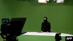 FILE - Masheed Barzz, an Afghan presenter for 1TV channel, appears on camera with her face covered by a veil in Kabul on May 25, 2022. Female journalists are banned from state-run media outlets, and those in the private sector can appear on TV only if their faces are covered. 