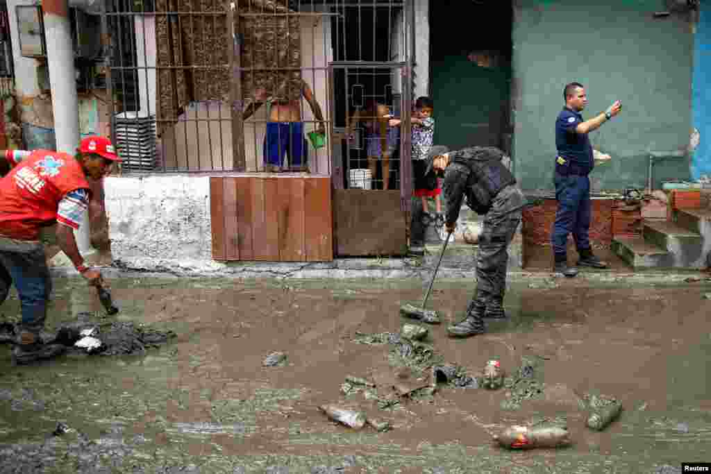 Un policía y un trabajador de la Alcaldía de Sucre retiran lodo de una de las calles afectadas por el desbordamiento del río.