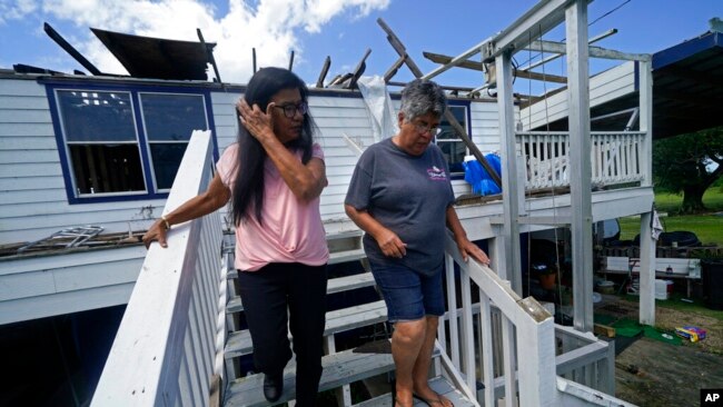 FILE - Louise Billiot, left, a member of the United Houma Nation Indian tribe, walks around the home of her friend and tribal member Irene Verdin , in Pointe-aux-Chenes, La., on May 26, 2022. Hurricane Ida heavily damaged Verdin's home.