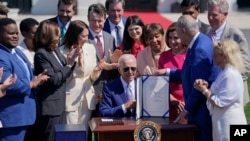 President Joe Biden holds the "CHIPS and Science Act of 2022" after signing it during a ceremony on the South Lawn of the White House, in Washington, Aug. 9, 2022.