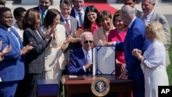 President Joe Biden holds the "CHIPS and Science Act of 2022" after signing it during a ceremony on the South Lawn of the White House, in Washington, Aug. 9, 2022.