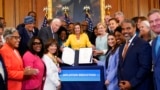 House Speaker Nancy Pelosi of Calif., surrounded by House Democrats, stands up after signing the Inflation Reduction Act of 2022 during a bill enrollment ceremony on Capitol Hill in Washington, Aug. 12, 2022.