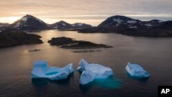 FILE - Large icebergs float away as the sun rises near Kulusuk, Greenland, Aug. 16, 2019. 