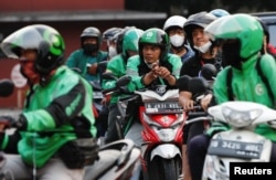 Pengendara gojek di atas sepeda motornya antre membeli bensin bersubsidi di SPBU Pertamina, di Jakarta, 22 Agustus 2022. (REUTERS/Ajeng Dinar Ulfiana)