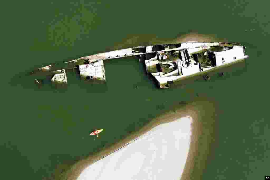 A kayaker paddles by the wreckage of a World War Two German warship in the Danube River near Prahovo, Serbia. The hulks of dozens of battle ships have been exposed on the river near the town of Prahovo after severe drought hit most of Europe this summer.