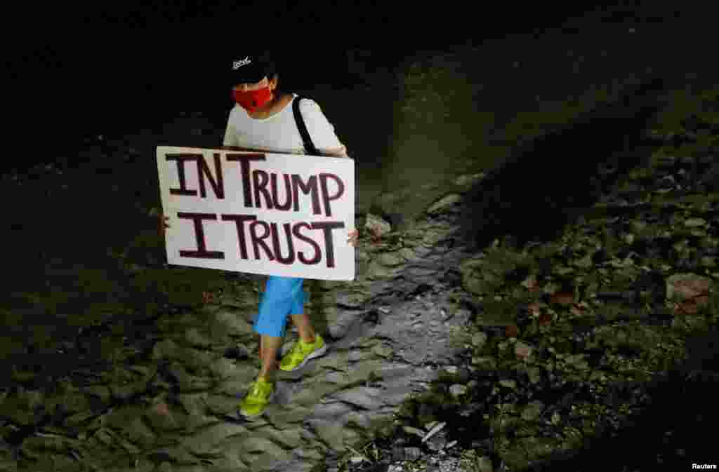 Seseorang memegang poster untuk mendukung mantan Presiden AS Donald Trump di luar rumahnya di Mar-a-Lago setelah Trump mengatakan bahwa agen FBI menggerebeknya, di Palm Beach, Florida. (Foto: Reuters)&nbsp;