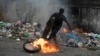 A protester kicks a burning tire during a protest in Port-au-Prince, Haiti, Aug. 22, 2022.