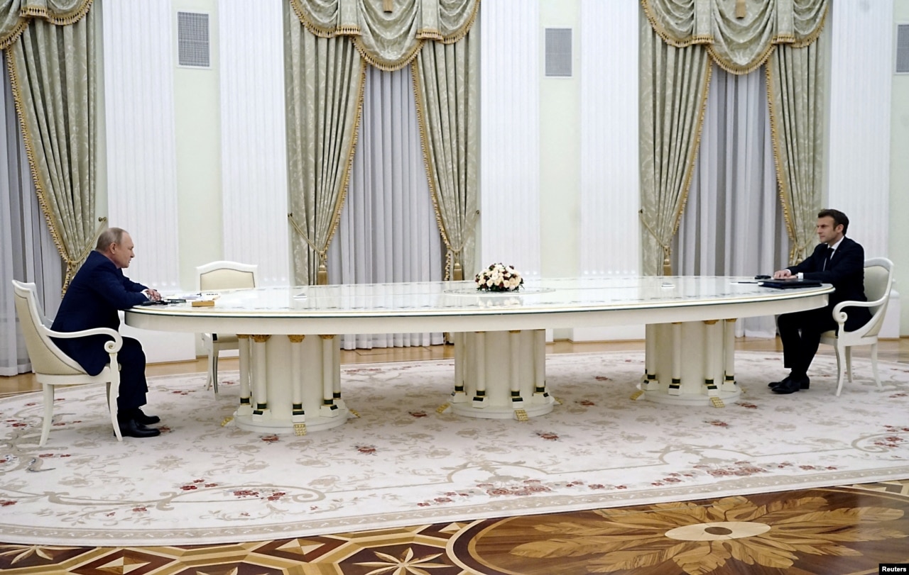 A photo of Russian President Vladimir Putin and French President Emmanuel Macron sitting at opposite ends of a long table.