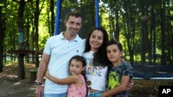 Volodymyr Zhdanov and his family pose in a park in Kyiv, Aug. 16, 2022.