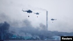 Helikopter berupaya memadamkan api kebakaran dengan menyiramkan air di atas tangki penyimpanan bahan bakar yang meledak di pelabuhan supertanker di Matanzas, Kuba, 9 Agustus 2022. (REUTERS/Alexandre Meneghini)