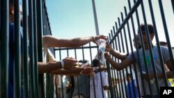 People reached out to grab water bottles as hundreds of migrants sought shelter outside an overcrowded asylum seekers center in Ter Apel, northern Netherlands, Aug. 25, 2022.