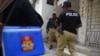 FILE - Policemen escort members of a polio vaccination team during a door-to-door vaccination campaign in Karachi, Pakistan, June 28, 2022.